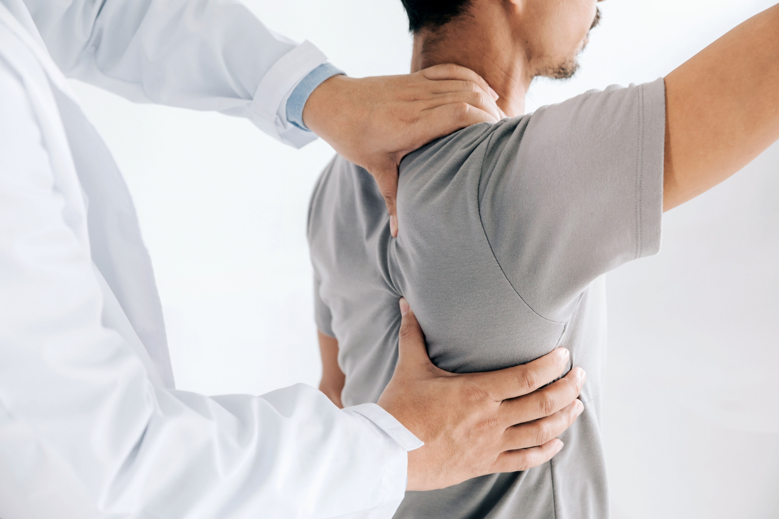 Physiotherapeut behandelt die Schulter eines Patienten